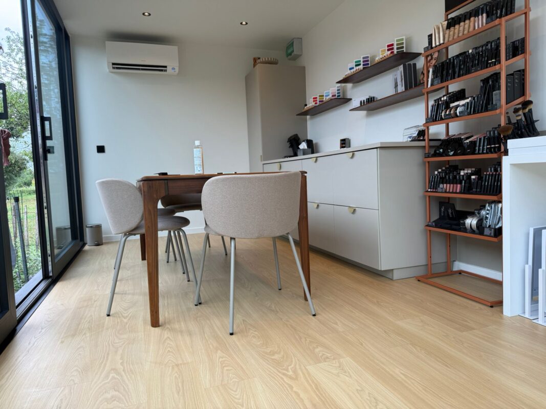 Atelier op maat van ROBCOR met houten tafel, vitrinekasten en een grote glazen schuifdeur naar de tuin.