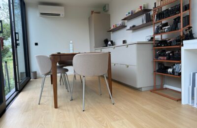 Atelier op maat van ROBCOR met houten tafel, vitrinekasten en een grote glazen schuifdeur naar de tuin.