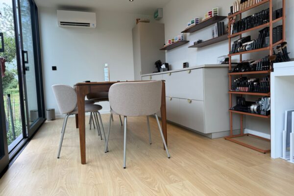 Atelier op maat van ROBCOR met houten tafel, vitrinekasten en een grote glazen schuifdeur naar de tuin.