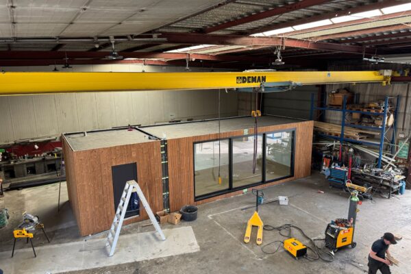 Modulaire unit van ROBCOR in aanbouw in de werkplaats, met houten structuur en een kraan boven het werkstuk.