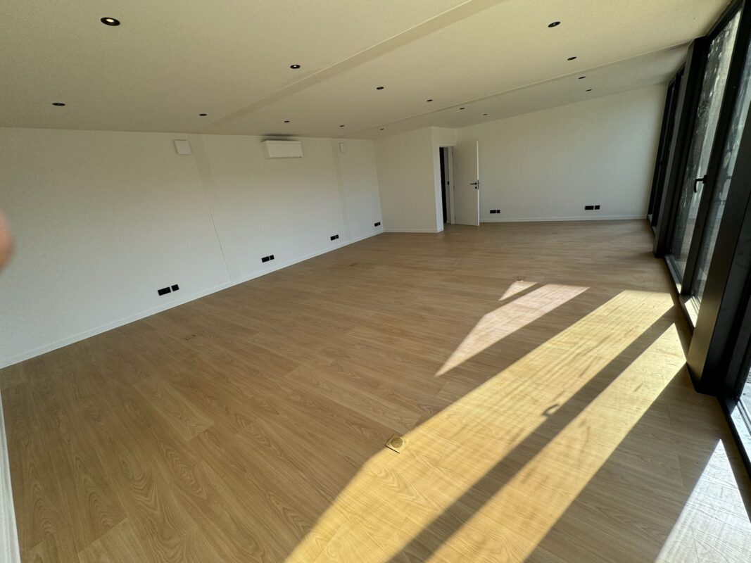 Minimalistische open bureauruimte in een kantoorunit van ROBCOR met houten vloer en grote ramen.