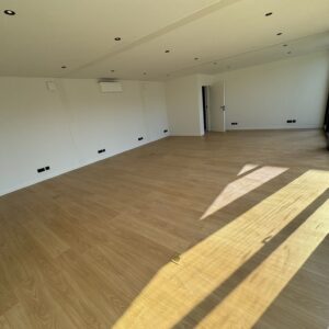 Minimalistische open bureauruimte in een kantoorunit van ROBCOR met houten vloer en grote ramen.