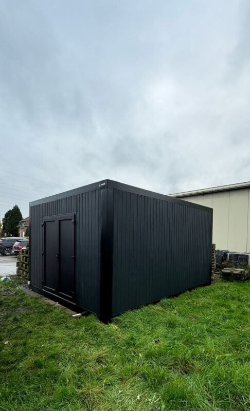 Zwarte modulaire opslagunit van ROBCOR op een grasveld in Destelbergen.