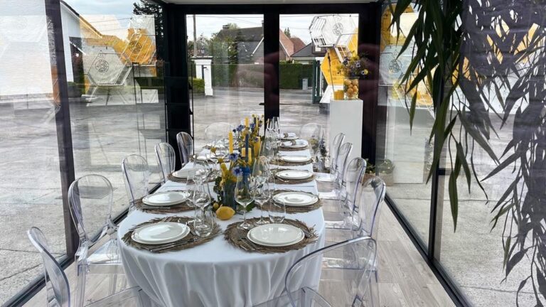 Lounge- en eetruimte in een modulaire unit van ROBCOR met grote glaspartijen, geschikt als poolhouse of feestruimte.