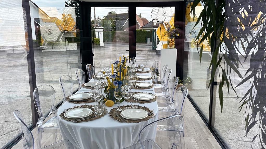 Lounge- en eetruimte in een modulaire unit van ROBCOR met grote glaspartijen, geschikt als poolhouse of feestruimte.