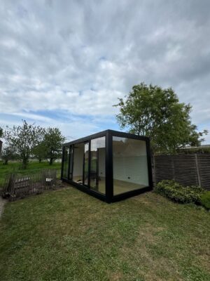 Modulaire kantoorunit van ROBCOR met zwarte omlijsting en grote glaspartijen in een tuin in Lokeren.