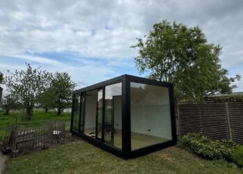 Modulaire kantoorunit van ROBCOR met zwarte omlijsting en grote glaspartijen in een tuin in Lokeren.