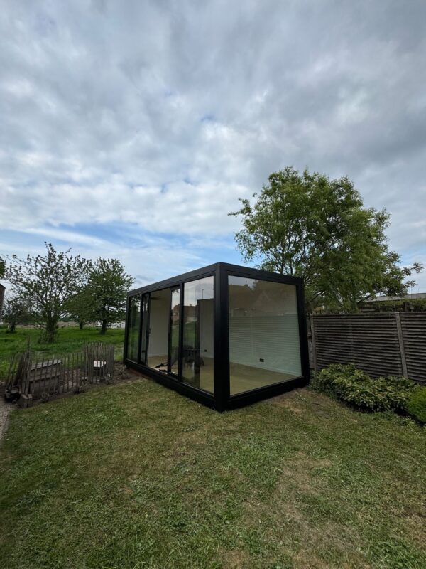 Modulaire kantoorunit van ROBCOR met zwarte omlijsting en grote glaspartijen in een tuin in Lokeren.