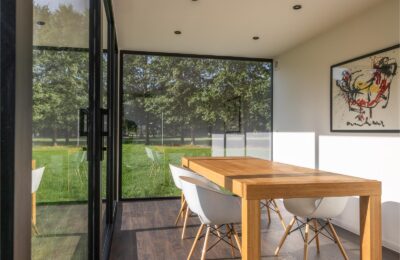 Modulaire woonunit op maat van ROBCOR met grote glaspartijen, houten eettafel en lichte leefruimte.