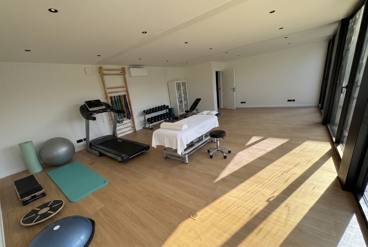 Kinepraktijk in een modulaire ROBCOR-unit met behandeltafel, loopband, klimrek met elastieken, dumbbellrek en balansmateriaal